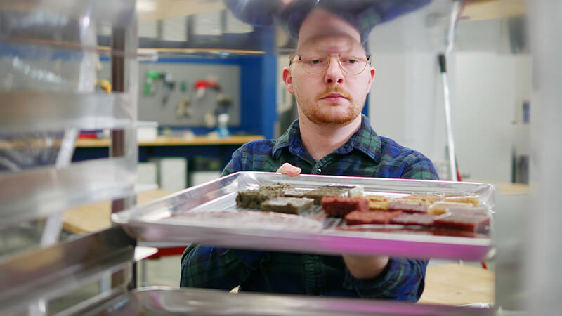 Student sliding tray of work into cabinet