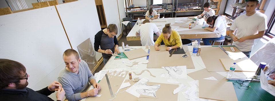 Large group of students sitting around table working on projects