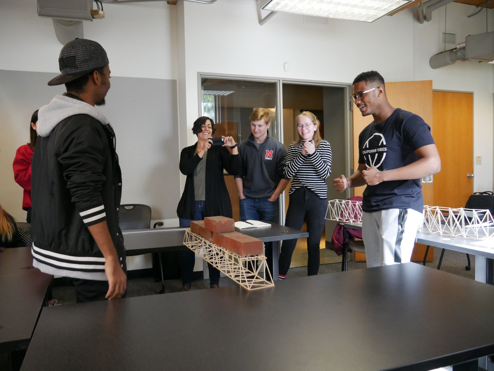 students placing bricks on top of a small wooden bridge