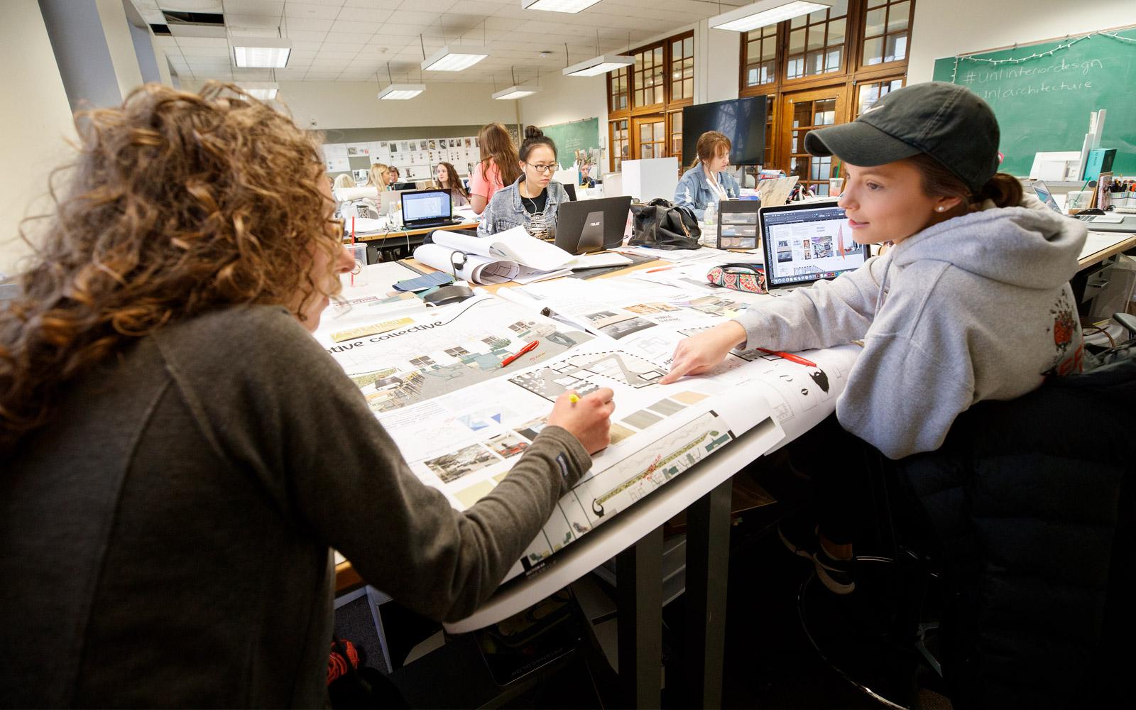 Students at drafting table discuss project