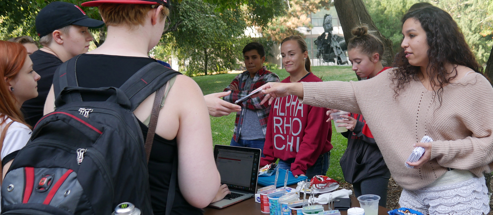 students handing out cards to other students at a booth