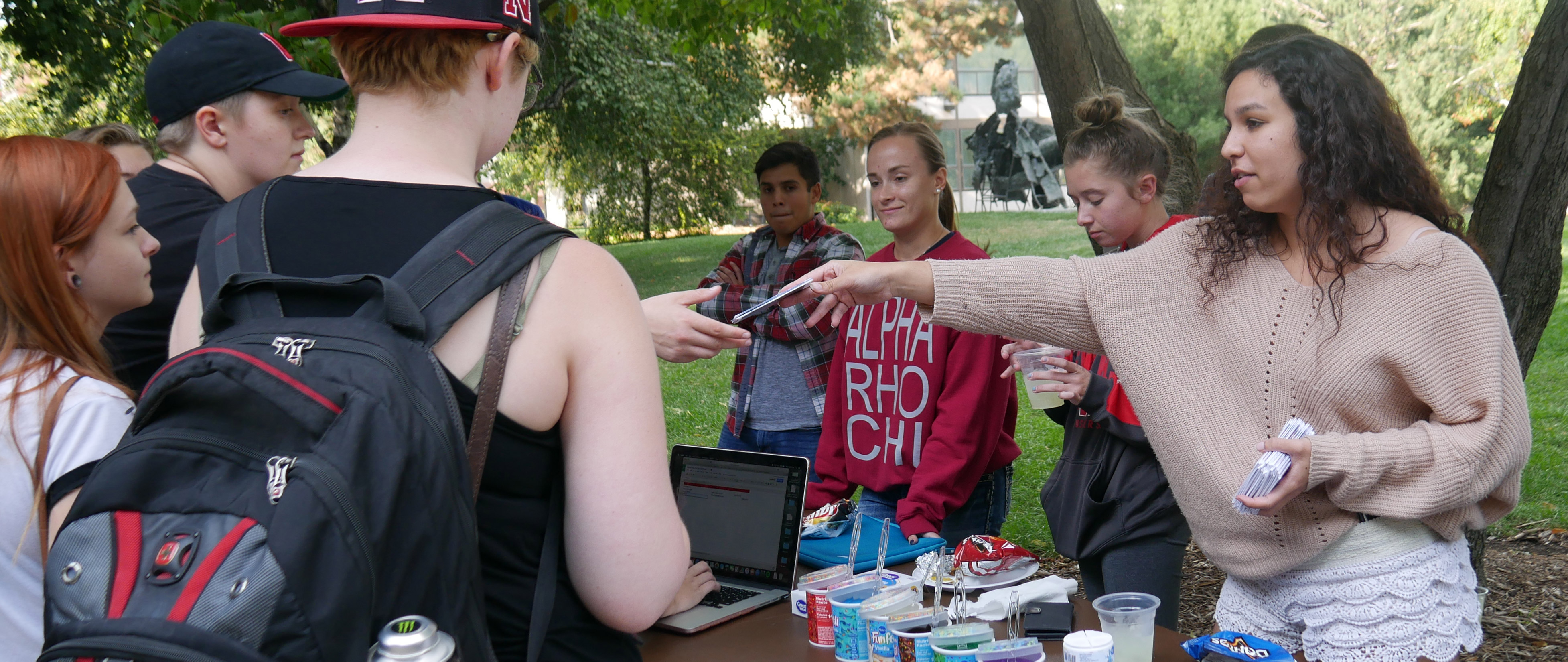 students handing out cards to other students at a booth