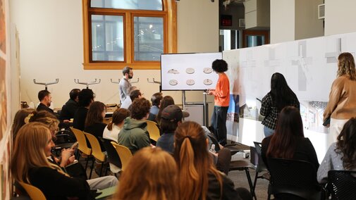 a student giving a presentation in front of a room full of peers