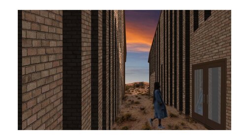Person walking between tall brick walls at sunset, with a desert landscape in the distance.