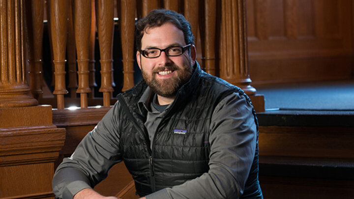 nathan bicak sitting on the stairs of the college of architecture and smiling