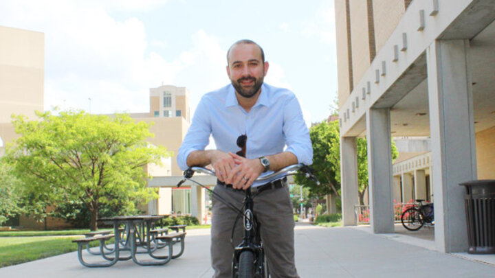 Daniel Piatowski smiling at the camera while resting on a bicycle