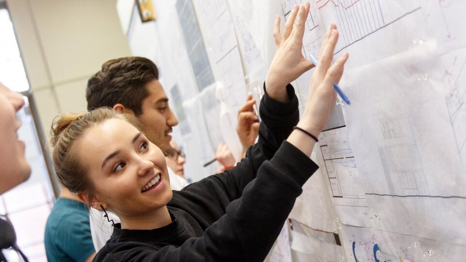 students drawing on a board filled with building layouts