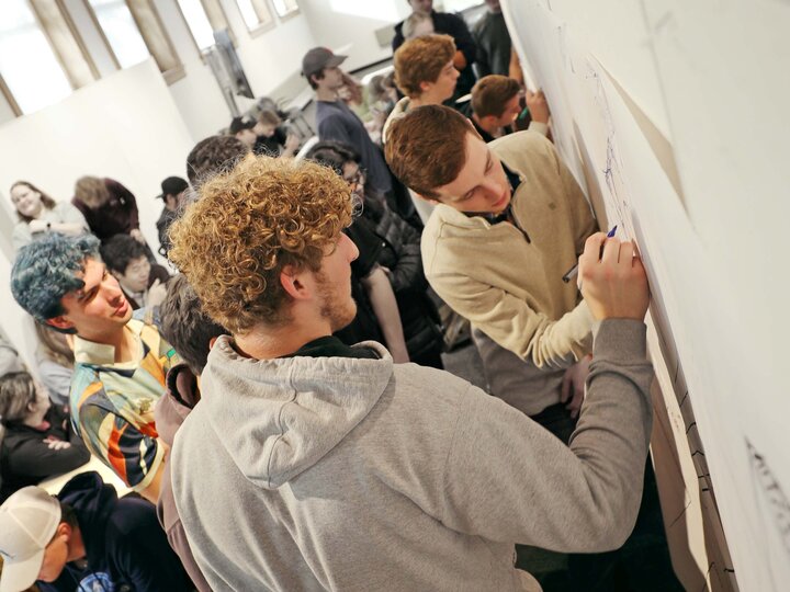 two students drawing on the whiteboard