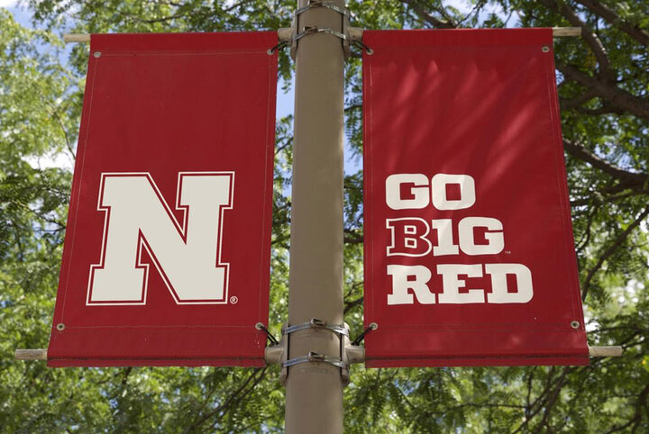 two flags with go big red and the unl "n" on a signpost