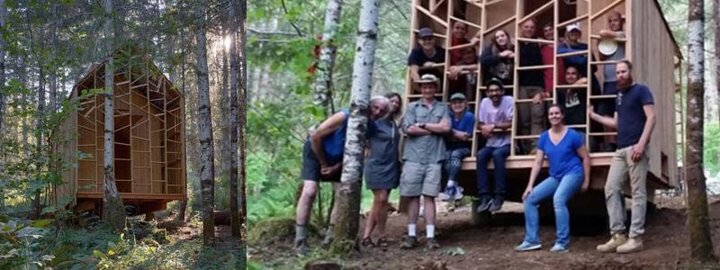 Students standing in front of building project outside in forest