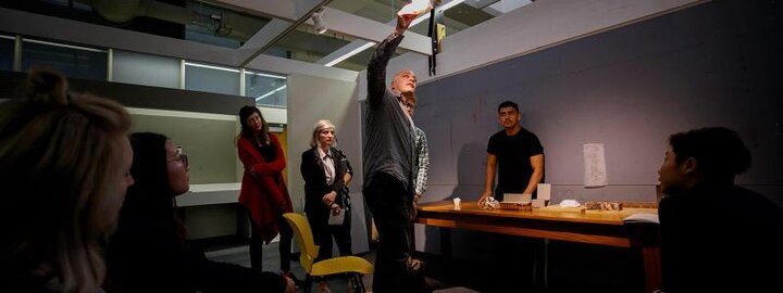 Students watching faculty member adjust lighting in room