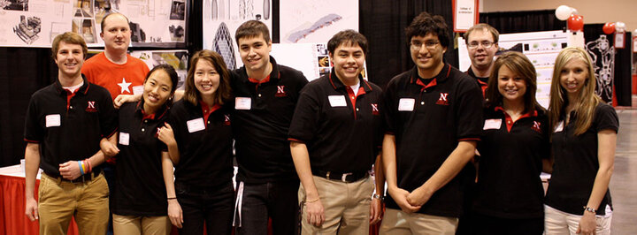 a group of unl students smiling in front of a booth